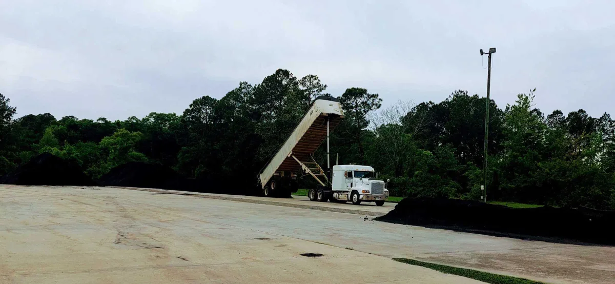 Bulk biochar being unloaded from a truck at an industrial yard