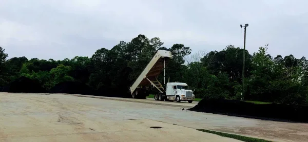 Bulk biochar being unloaded from a truck at an industrial yard